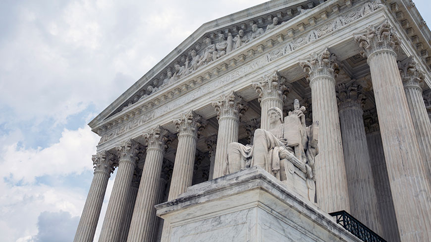 The Supreme Court building in Washington, D.C., viewed from a low angle, showing its columns and pediment under a cloudy sky.