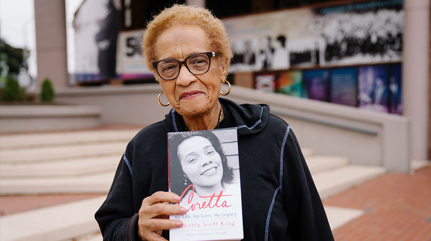 An older woman with glasses holds up the biography of Coretta Scott King at the King Center in Atlanta, Georgia.
