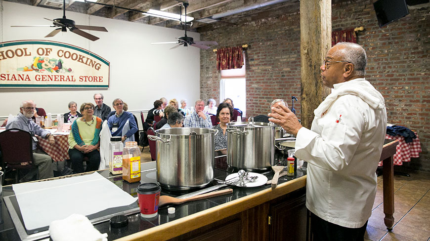 A chef teaches a cooking class to a group of attentive adults at the Louisiana School of Cooking in New Orleans.