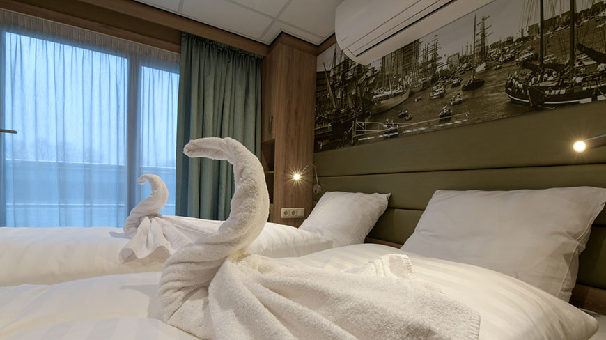 Two beds with towels folded into swans sit in a cabin on the De Holland ship in the Netherlands.