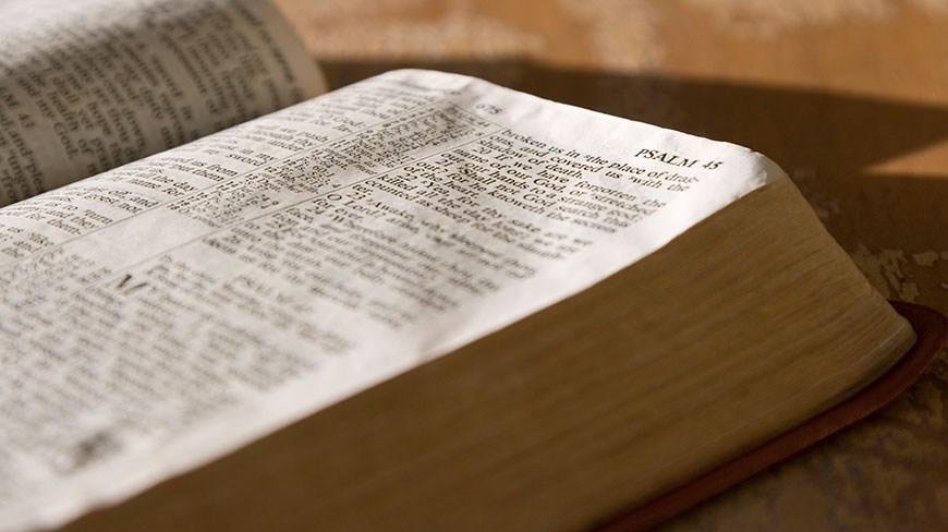 A close-up, angled view of an open Bible, showing the text of Psalm 45 under warm lighting.