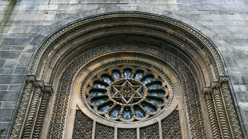 An ornate stone rose window with a Star of David at the center on the Ohab Zedek Temple in New York City.