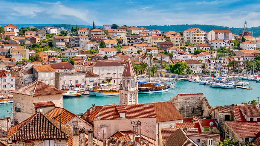 The coastal town of Trogir, Croatia, seen from above, with its red-tiled roofs and a harbor full of boats.
