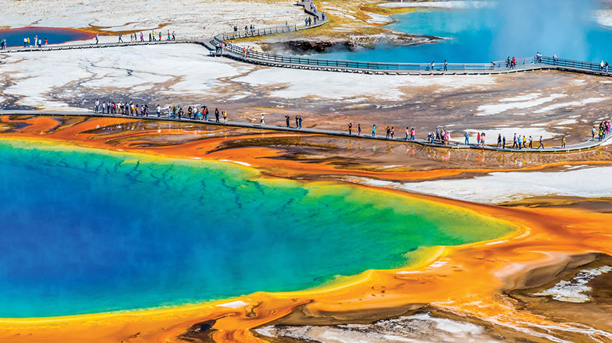 An aerial view shows tourists on a boardwalk surrounding the vibrant Grand Prismatic Spring in Yellowstone National Park, Wyoming.