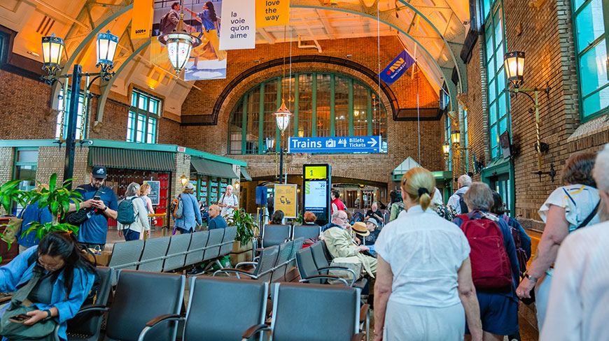 A group of travelers waits inside the historic Gare du Palais train station in Old Québec, Canada, under its high, arched brick ceiling.