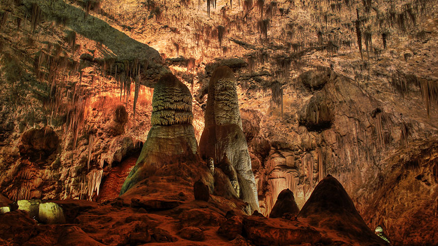 Massive stalagmites and stalactites fill the warmly lit interior of Carlsbad Caverns National Park in New Mexico.