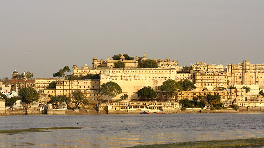 The magnificent City Palace complex in Udaipur, India, rises above the tranquil waters of a lake.
